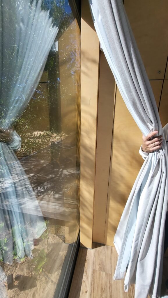 Persona abriendo cortinas hacia un ventanal con vistas al exterior, simbolizando la transparencia y claridad en el análisis de viabilidad técnica y rentabilidad de activos inmobiliarios en Alicante
