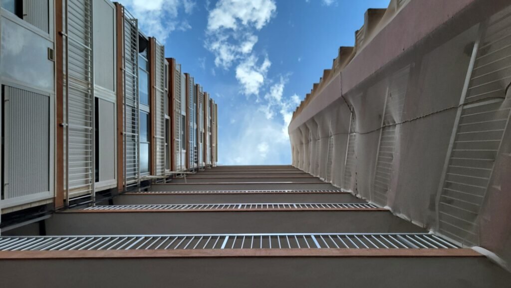 Perspectiva vertical inferior entre dos edificios de apartamentos en Alicante, uno con mallas de seguridad y el otro con balcones y barandillas blancas, simbolizando la auditoría técnica que realiza Levita Properties como Personal Shopper Inmobiliario